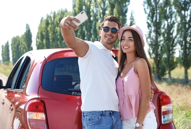 Photo of Happy young couple taking selfie near car on road