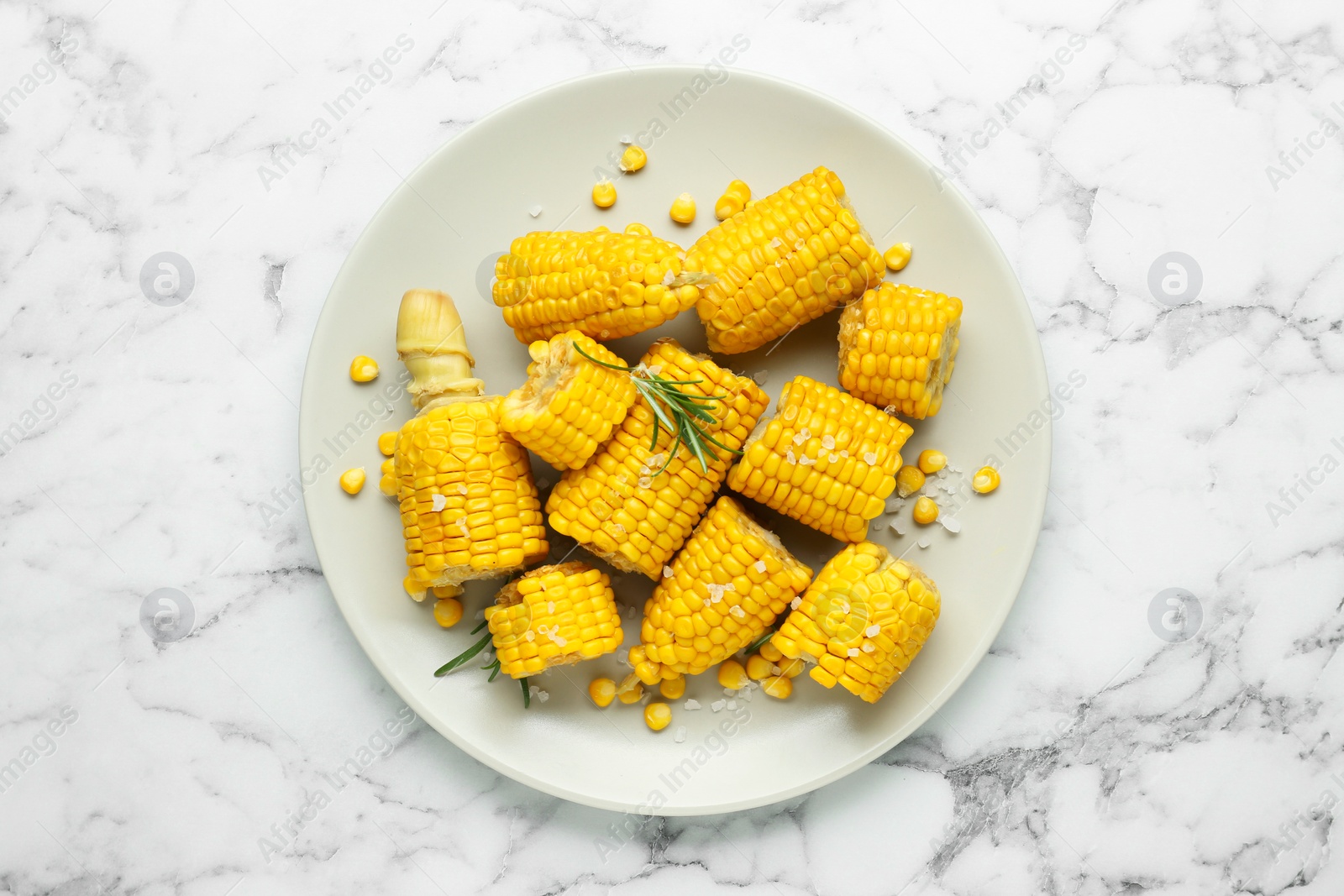 Photo of Plate with tasty cooked corn cobs on white marble table, top view