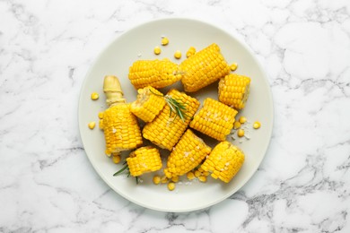 Plate with tasty cooked corn cobs on white marble table, top view