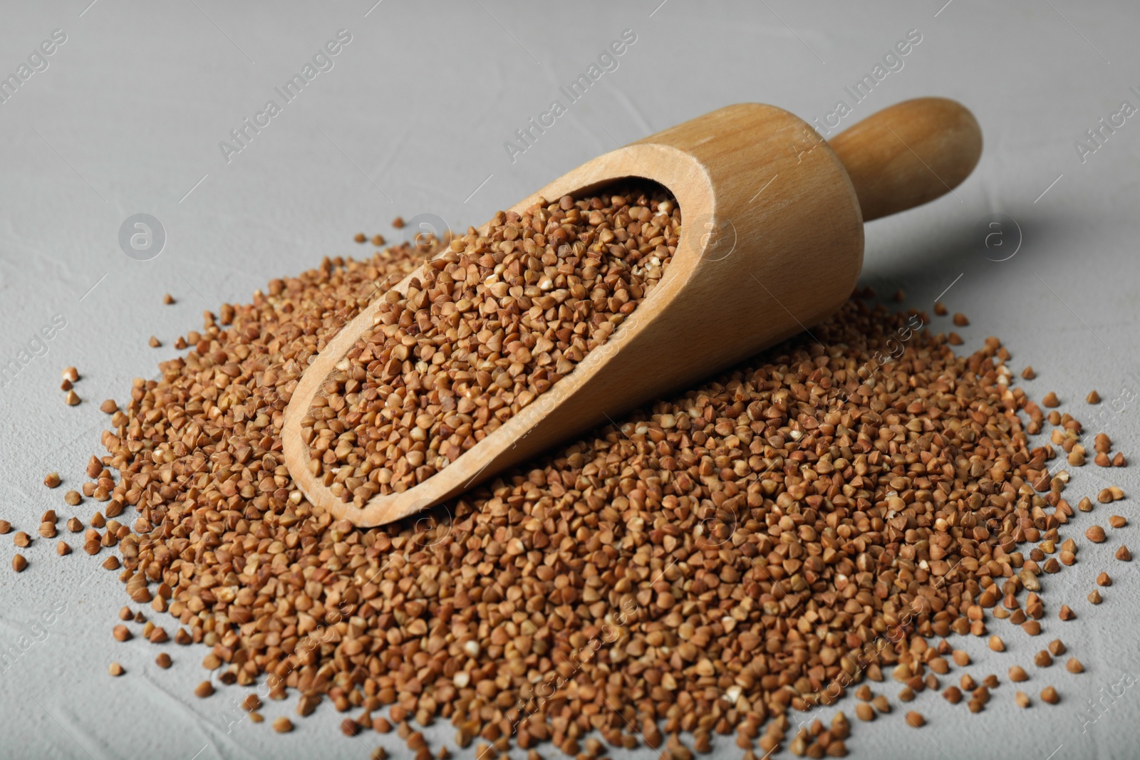 Photo of Wooden scoop with uncooked buckwheat on table