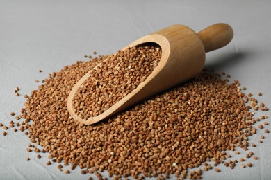 Photo of Wooden scoop with uncooked buckwheat on table