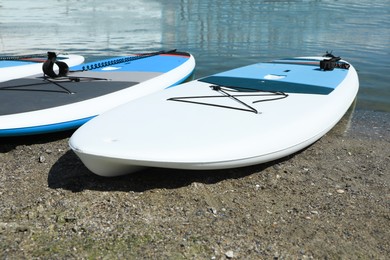 Photo of Different paddle boards on sand near river, closeup