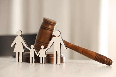 Photo of Law concept. Gavel and figures of parents with children on white wooden table, closeup