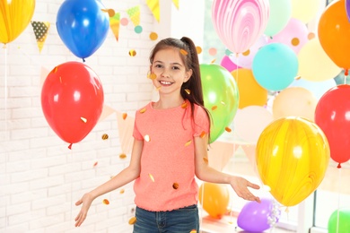 Happy girl near bright balloons at birthday party indoors