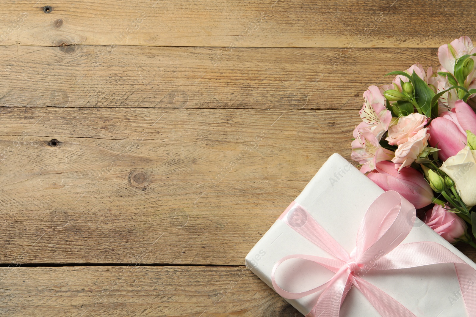 Photo of Happy Mother's Day. Beautiful flowers and gift box on wooden table, flat lay. Space for text