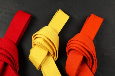 Photo of Colorful karate belts on gray background, flat lay