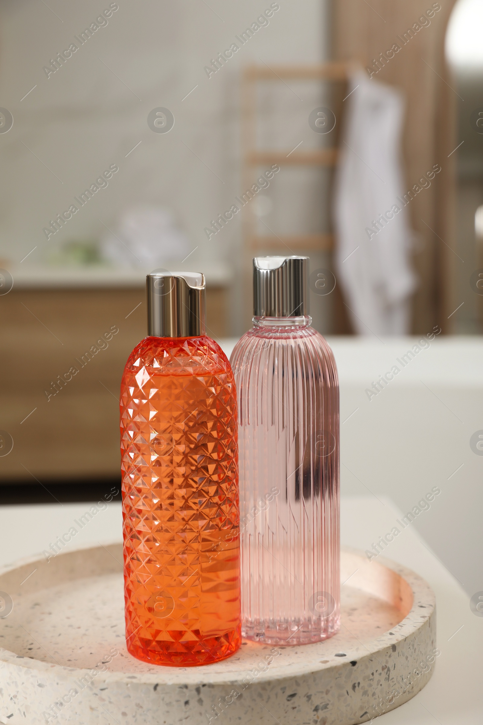 Photo of Bottles of shower gels on white table in bathroom