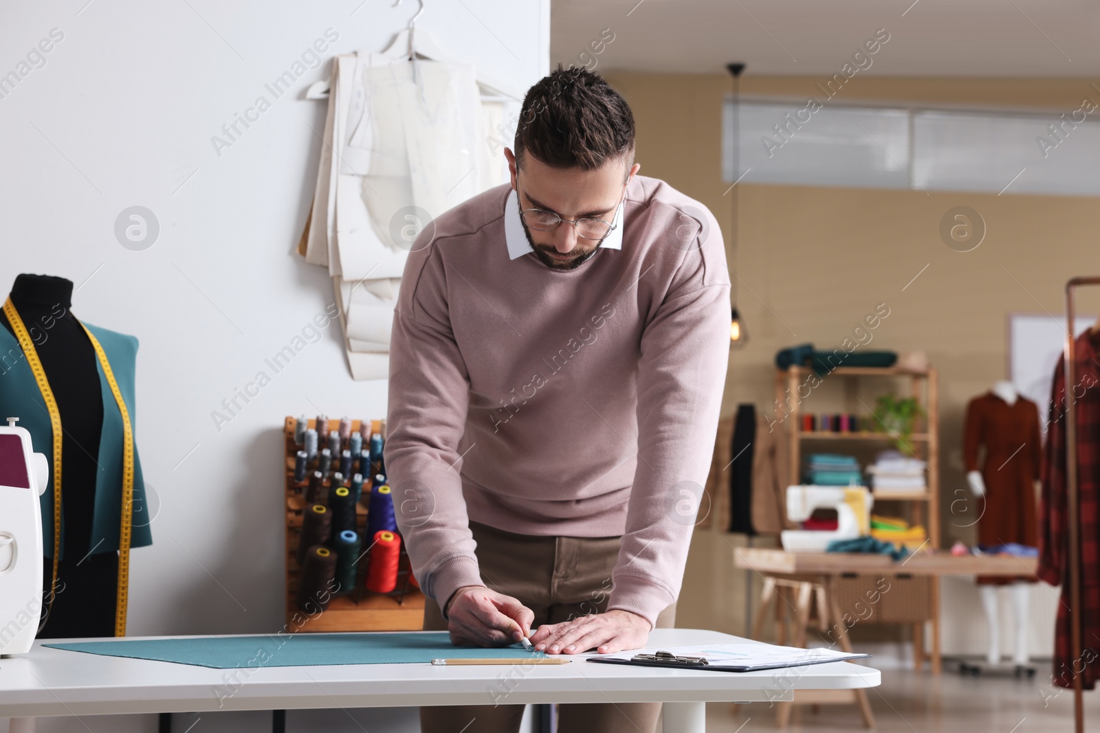 Photo of Dressmaker marking fabric with chalk in workshop