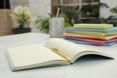 Photo of Open notebook and pen on white wooden table. Personal planning