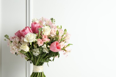 Photo of Beautiful bouquet of fresh flowers near white wall. Space for text