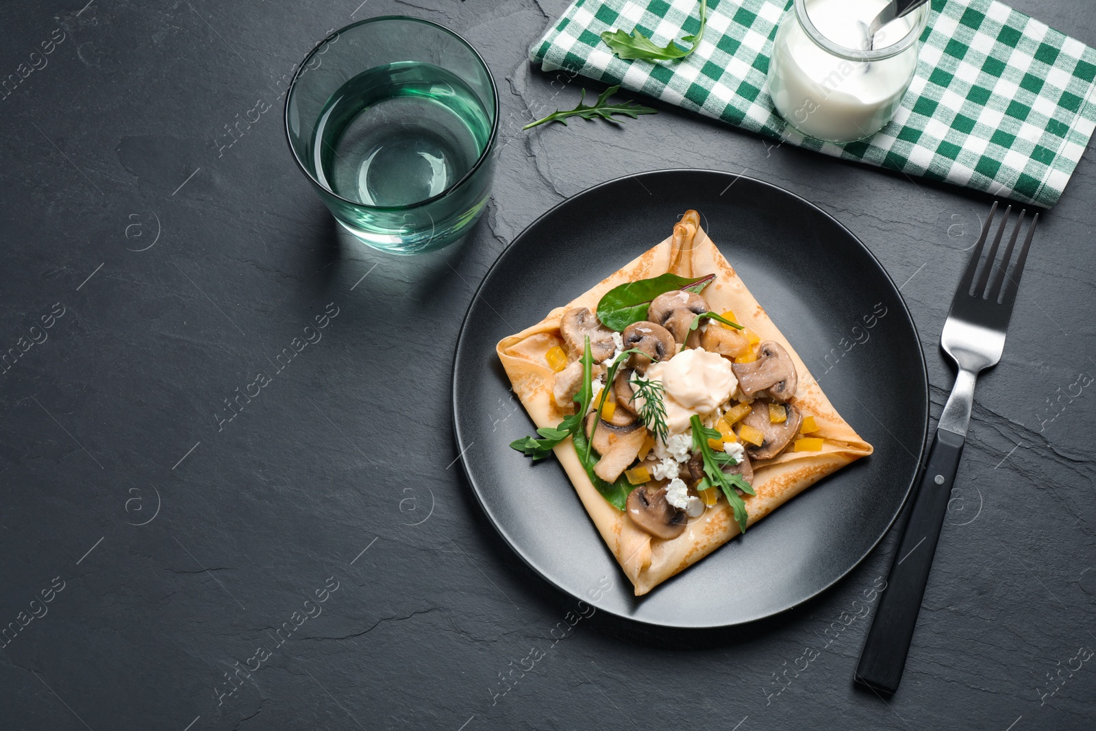 Photo of Delicious breakfast with thin pancakes on black table, flat lay. Space for text