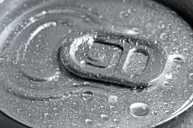 Aluminum can of beverage covered with water drops as background, closeup