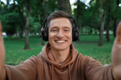 Photo of Smiling man in headphones taking selfie in park