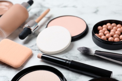 Photo of Composition with powder, skin foundation and beauty accessories on marble background