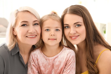 Photo of Happy young woman with her mother and daughter at home