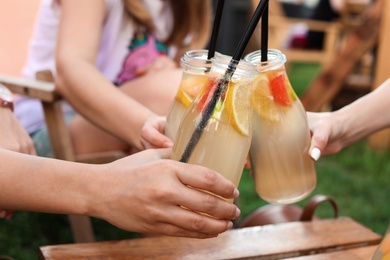 Young women with bottles of tasty lemonade outdoors, closeup