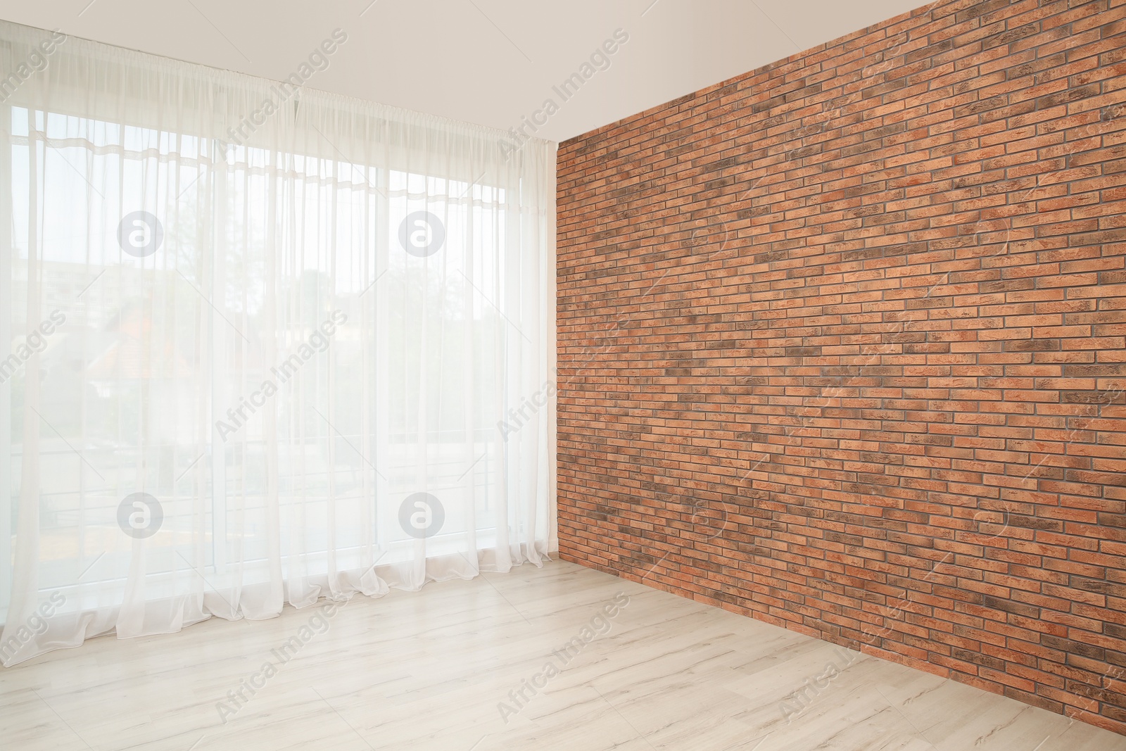 Photo of Empty room with brick wall and large window