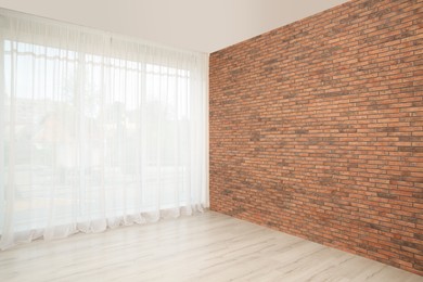 Photo of Empty room with brick wall and large window