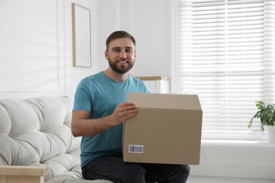 Happy young man with parcel at home