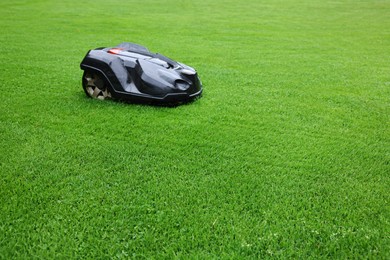 Modern lawn mower on green grass outdoors. Space for text