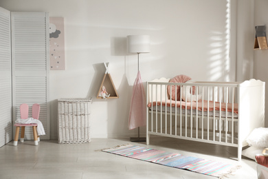 Photo of Cute baby room interior with crib and decor elements