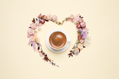 Beautiful heart shaped floral composition with cup of coffee on beige background, flat lay