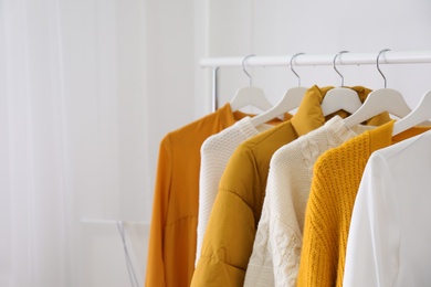 Photo of Rack with stylish warm clothes indoors, closeup. Space for text