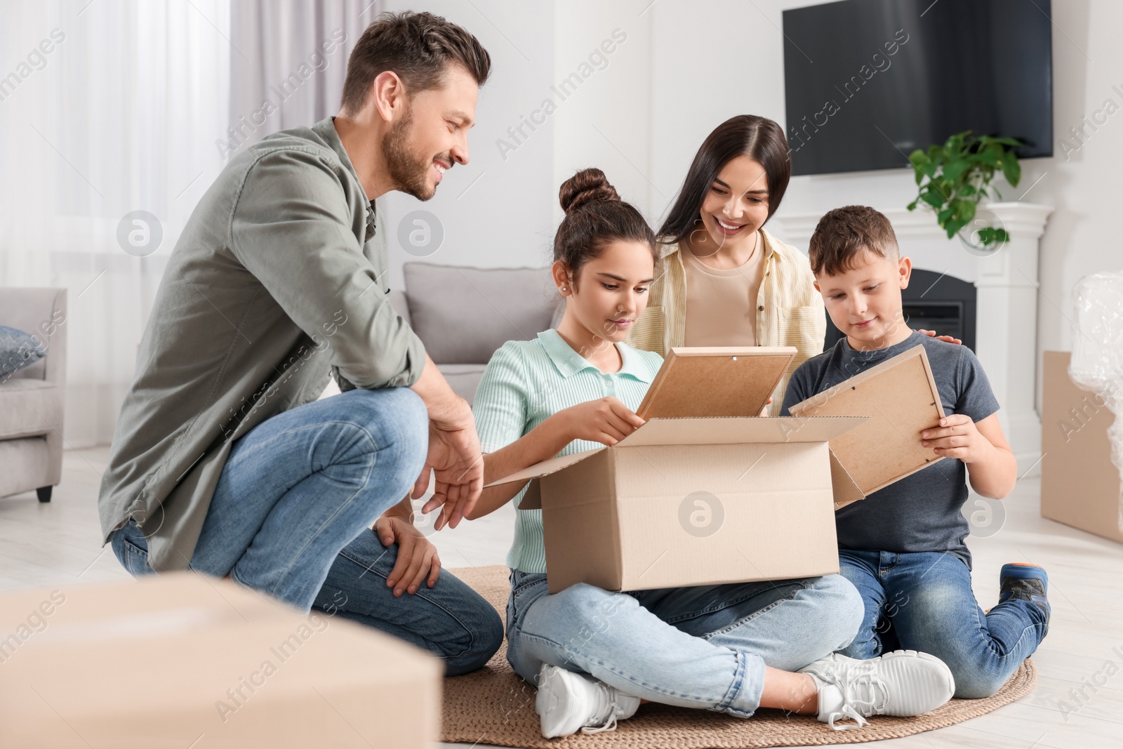 Photo of Happy family settling into new house and unpacking boxes on floor. Moving day