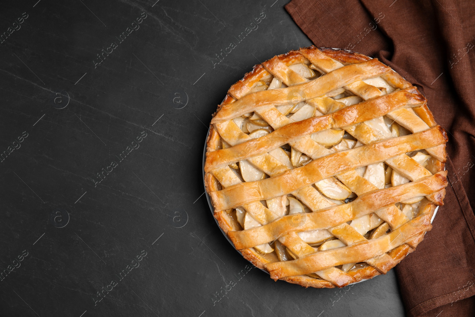 Photo of Delicious traditional apple pie on black table, top view. Space for text