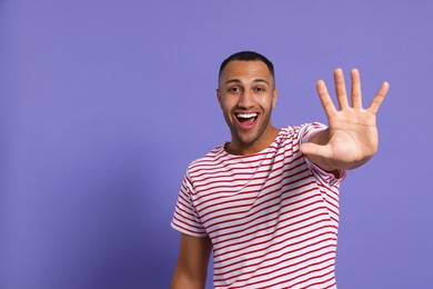 Man giving high five on purple background. Space for text