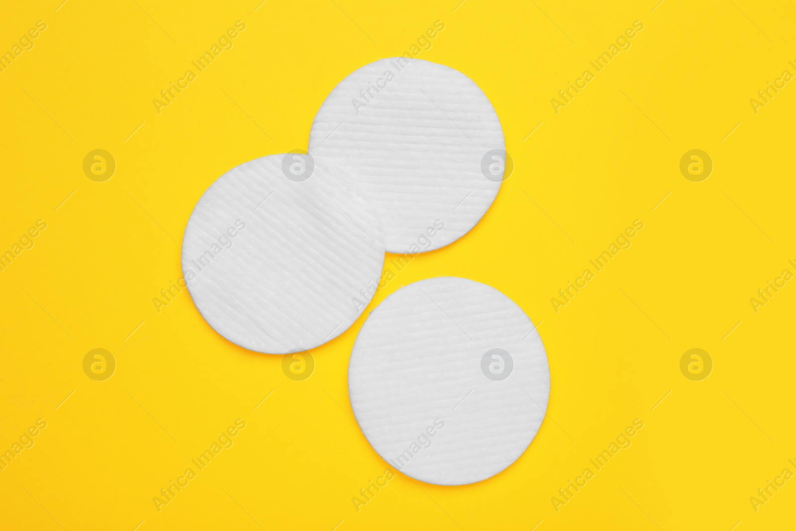 Photo of Soft clean cotton pads on yellow background, flat lay