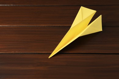 Photo of Handmade paper plane on wooden table, closeup. Space for text