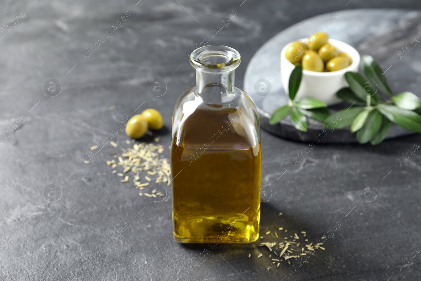 Photo of Bottle of fresh olive oil on dark grey table