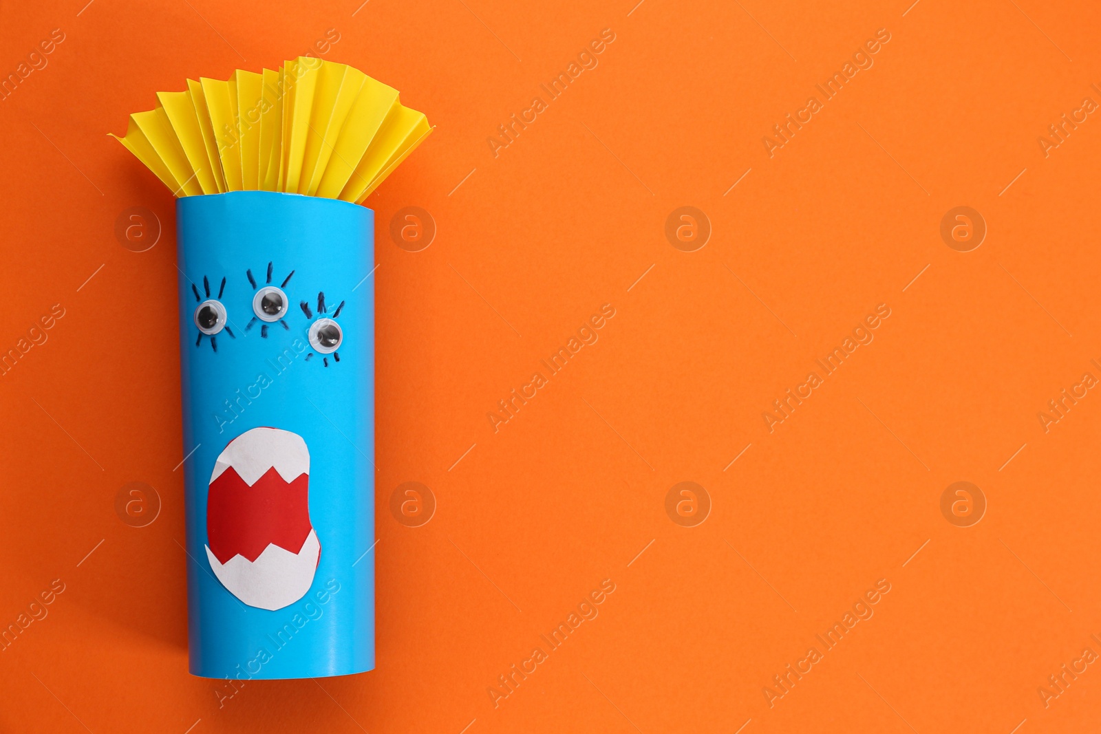 Photo of Funny blue monster on orange background, top view with space for text. Halloween decoration