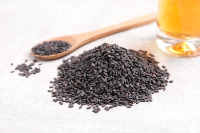 Black sesame seeds and oil on light table, closeup