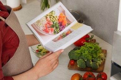 Woman with recipe book in kitchen, closeup