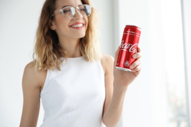 Photo of MYKOLAIV, UKRAINE - NOVEMBER 28, 2018: Young woman with Coca-Cola can indoors