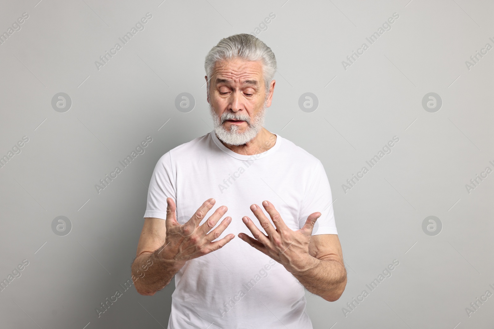 Photo of Arthritis symptoms. Man suffering from pain in hands on gray background