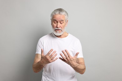 Arthritis symptoms. Man suffering from pain in hands on gray background