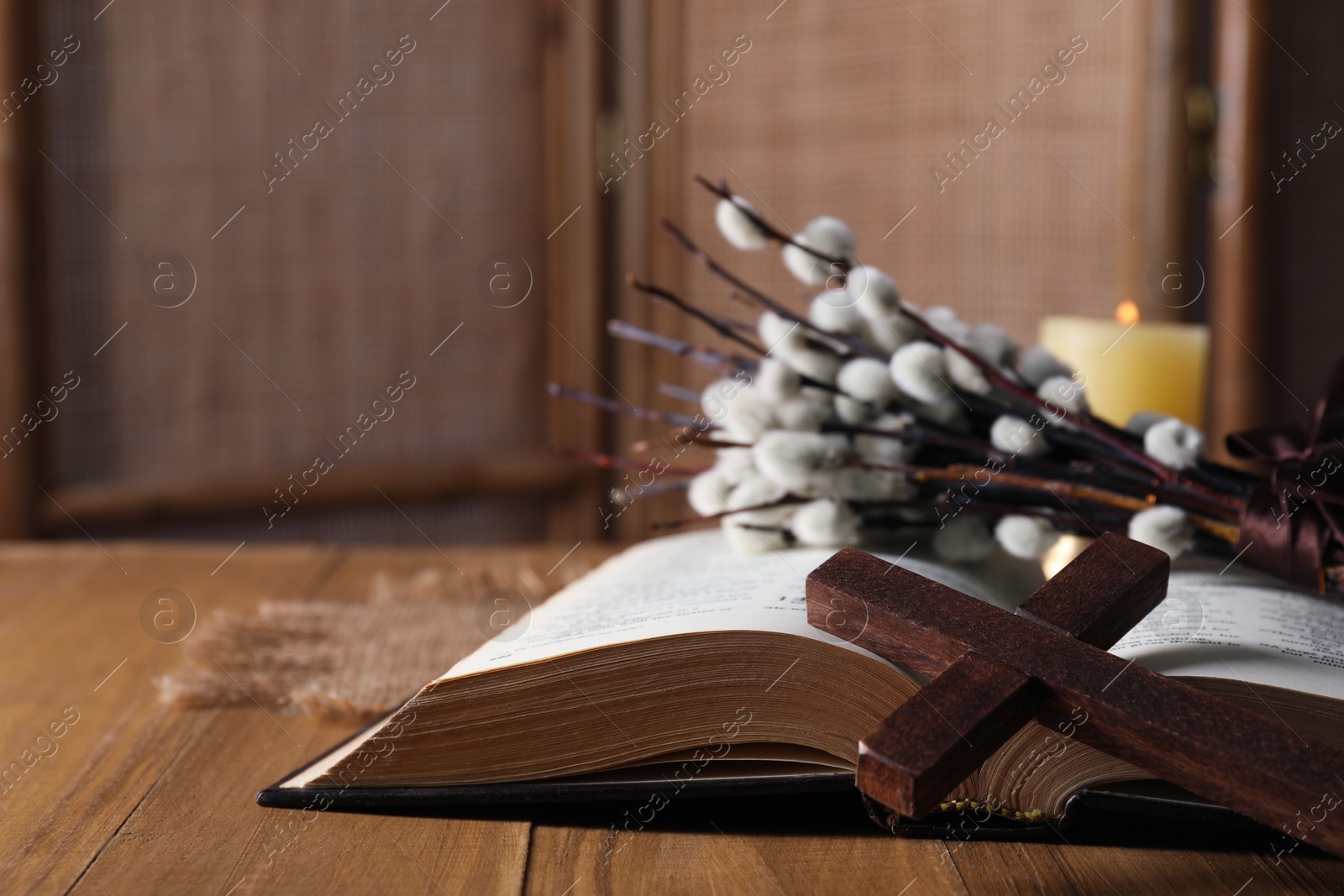 Photo of Cross, Bible and willow branches on wooden table, closeup. Space for text