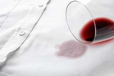 Photo of Overturned glass and spilled exquisite red wine on white shirt. Space for text