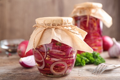 Photo of Jars of pickled onions on wooden table