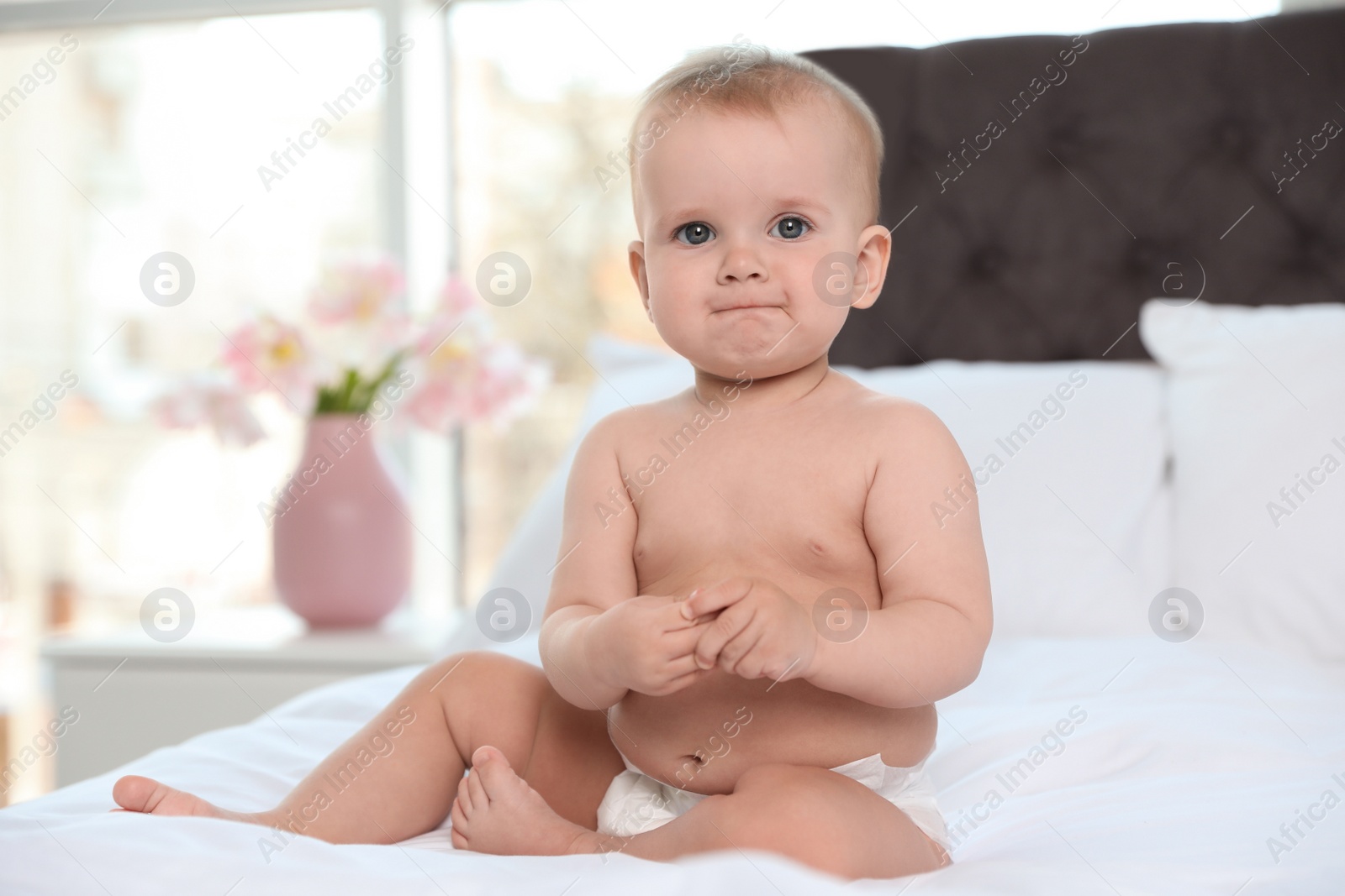 Photo of Cute baby in diaper on bed at home