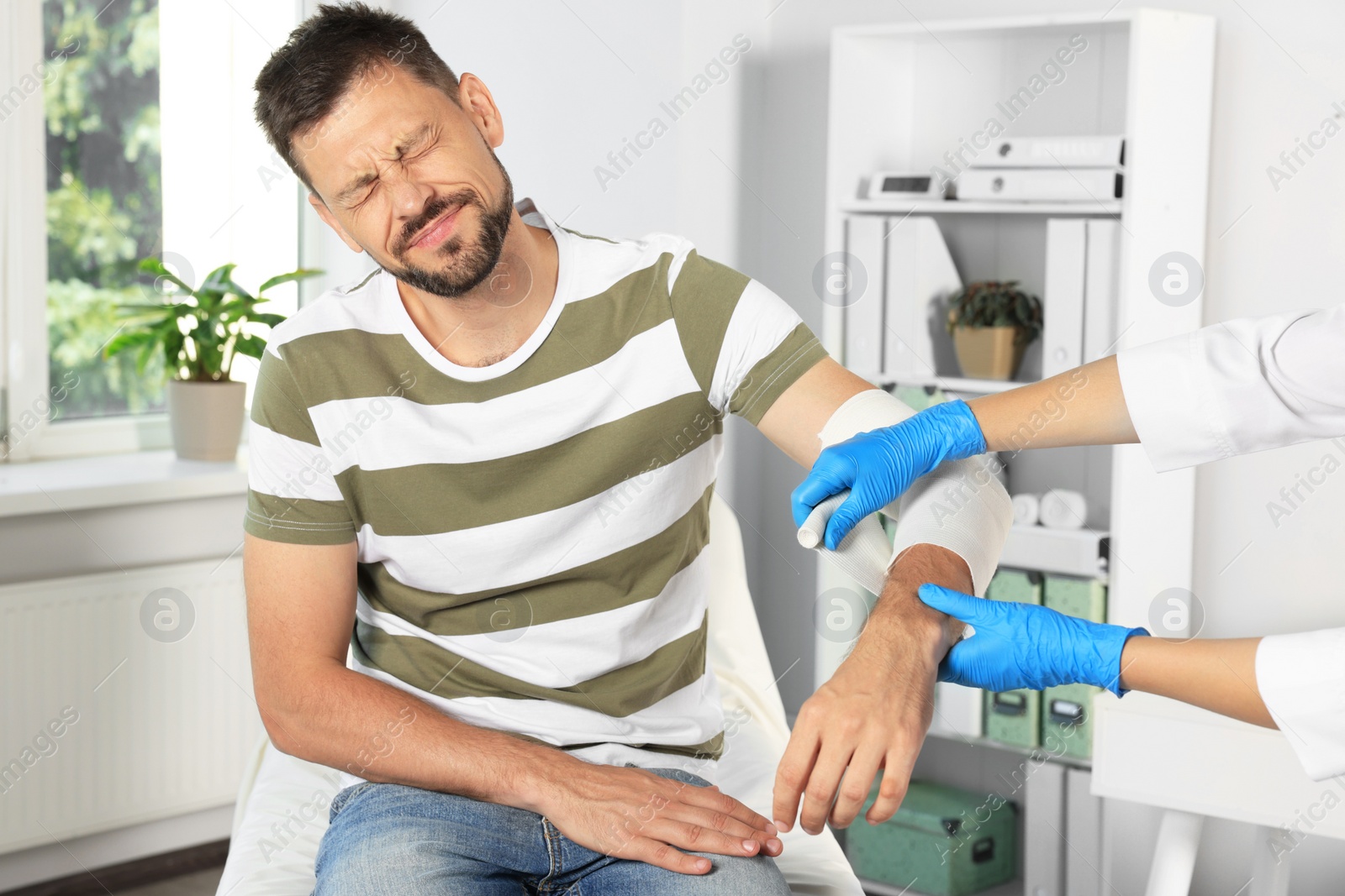 Photo of Doctor applying bandage onto patient's arm in hospital