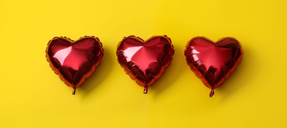 Red heart shaped balloons on yellow background. Valentine's Day celebration