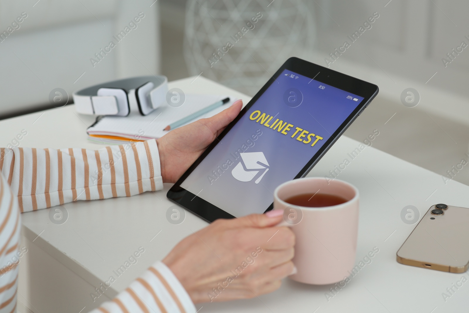 Photo of Woman taking online test on tablet at desk indoors, closeup