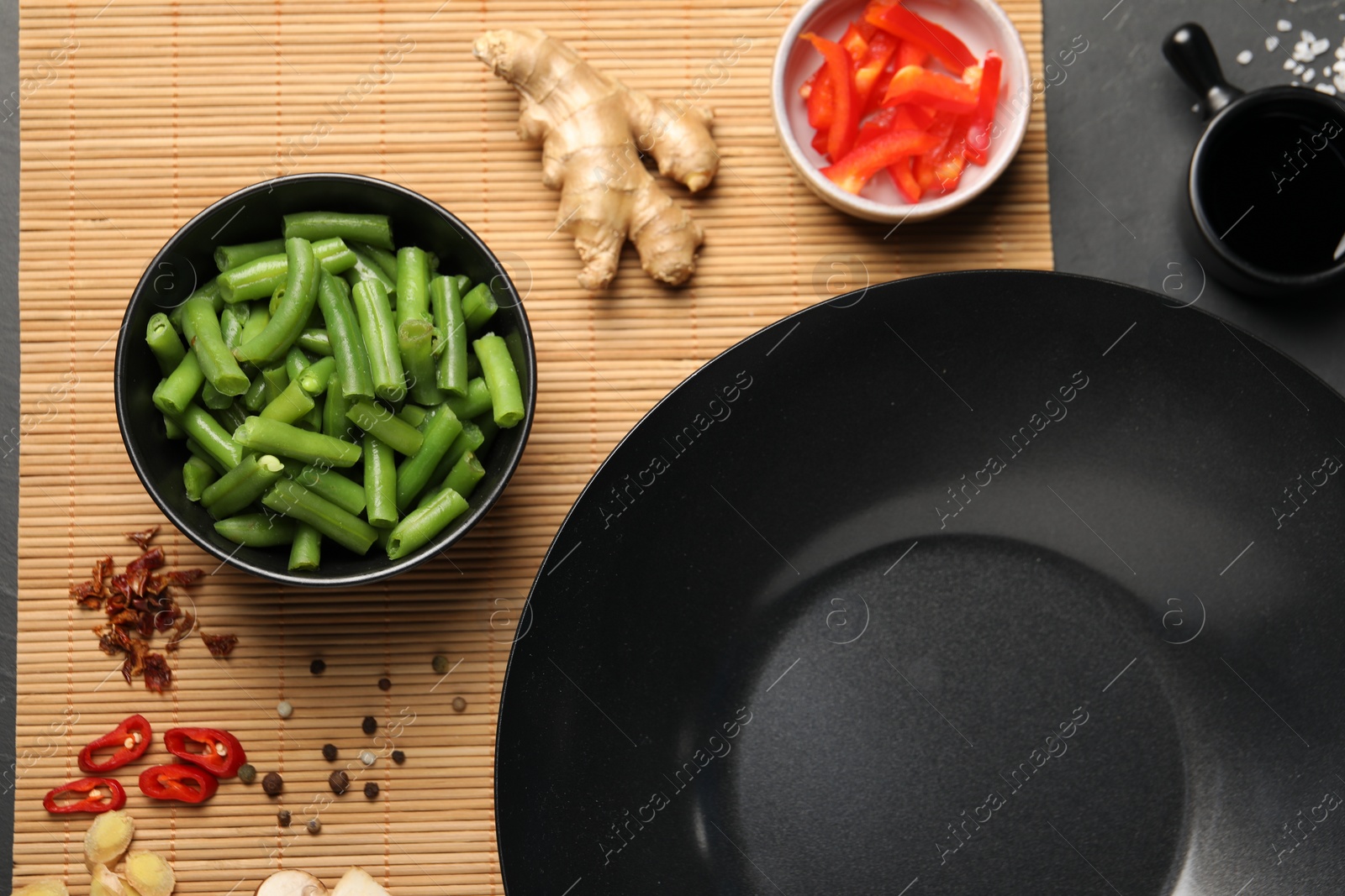 Photo of Flat lay composition with black wok, spices and products on dark table