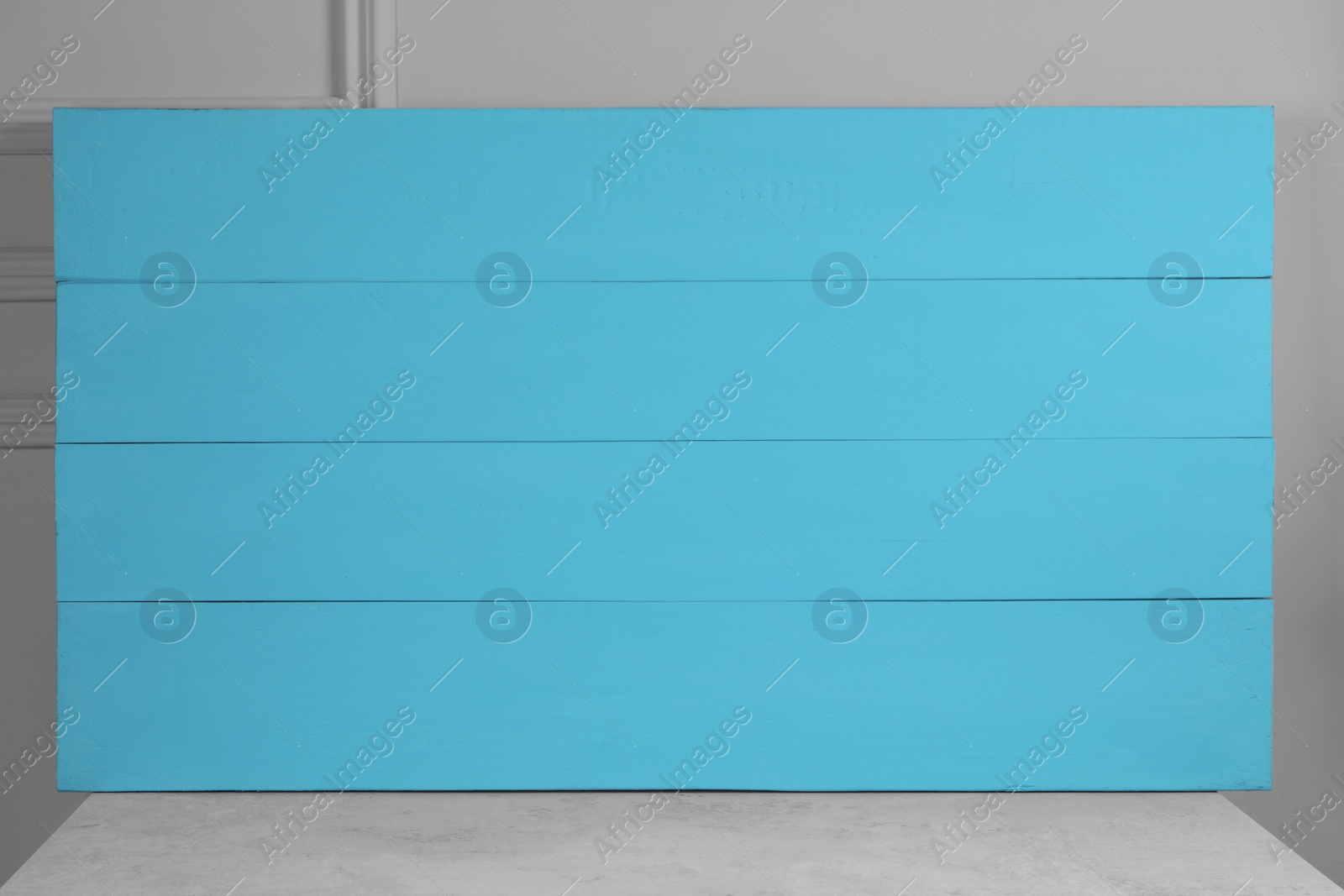 Photo of Texture of light blue wooden board on table near wall