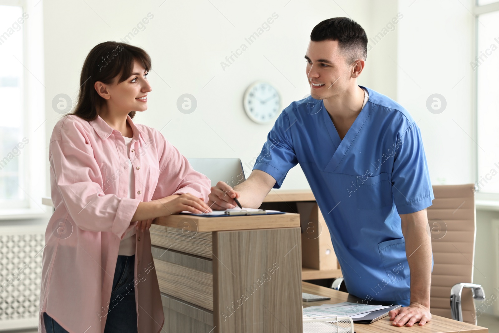 Photo of Smiling medical assistant working with patient at hospital reception