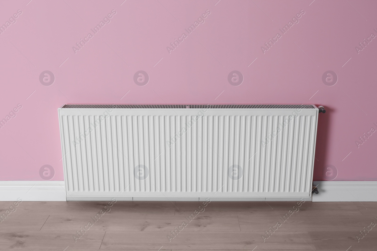 Photo of Modern radiator on color wall indoors. Central heating system